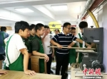 负责指导的王坚老师正在教导学生用机器加工木材。　钟升　摄 - 江苏新闻网