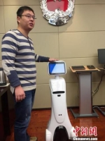 江苏省司法厅工作人员许奇介绍实体“智慧小司”机器人。　朱晓颖 摄 - 江苏新闻网