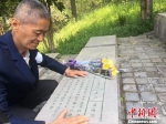 刘兆德抚摸着碑上名字，为舅舅送上一束鲜花。　申冉 摄 - 江苏新闻网