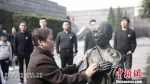 74岁的陈金凤擦拭着母亲的铜像。　田宇宙 摄 - 江苏新闻网