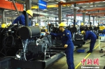 图为技术工人在整洁的厂房中进行“人机配合”，高效率生产机器。　朱志庚 摄 - 江苏新闻网
