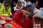 戴着“小猪”造型帽子的孩子们喝腊八粥，祈福新年。　泱波 摄 - 江苏新闻网