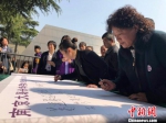 5日是清明节。清晨，南京大屠杀幸存者后代在“南京大屠杀幸存者后代传承记忆行动”卷轴上悉数落笔签名，以表达参与到南京大屠杀历史记忆传承行动中来。　朱晓颖 摄 - 江苏新闻网