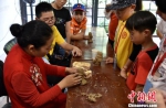 孩子们围在陶俑制作老师周围，学习并亲手制作汉武士俑。　朱志庚 摄 - 江苏新闻网