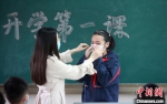 学生在老师的指导下，学习正确佩戴口罩的方法。　孟德龙　摄 - 江苏新闻网