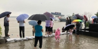 19日，降雨时断时续。在位于长江南京段的幕燕滨江风光带，人们在五马渡码头观看长江水位。　朱晓颖　摄 - 江苏新闻网