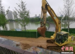 大型渣土车和挖掘机在把建筑垃圾运走、填平河堤恢复原状。　葛勇 摄 - 江苏新闻网