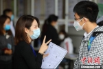 戴着口罩的求职者在招聘会现场与用人单位工作人员交谈。(资料图) 泱波 摄 - 江苏新闻网
