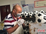 王学兵正在给缝制好的足球“上胆”。　刘林　摄 - 江苏新闻网