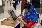 身着泉州惠安女服饰的非遗传承人展示惠安影雕工艺。　崔佳明 摄 - 江苏新闻网