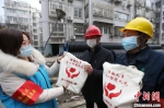 扬州一社区志愿者向“就地过年”人员发放爱心防疫礼包。　董辉 摄 - 江苏新闻网
