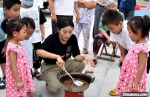 孩子们围在煎制金蝉现场，眼巴巴地等着美食出锅。　朱志庚 摄 - 江苏新闻网