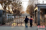 徐州市兴东实验学校门口，两名小学生在门外朝里张望，希望疫情尽快散去，他们能早点回到学校上课。　朱志庚　摄 - 江苏新闻网