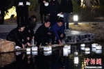 恩来干部学院教职工在一盏盏河灯上写下话语，河灯伴随着河水东流，寄托无限哀思。　于天 摄 - 江苏新闻网
