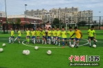 学生穿着足球服和教练合影。刘裔艺 摄 - 江苏新闻网