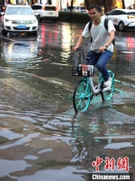 梅雨期间，市民在积水中出行。泱波 摄 - 江苏新闻网
