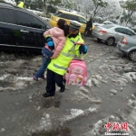 被交警叔叔“举高高”跨过雪水、抱进学校的孩子们。　南京交警供图 摄 - 江苏新闻网